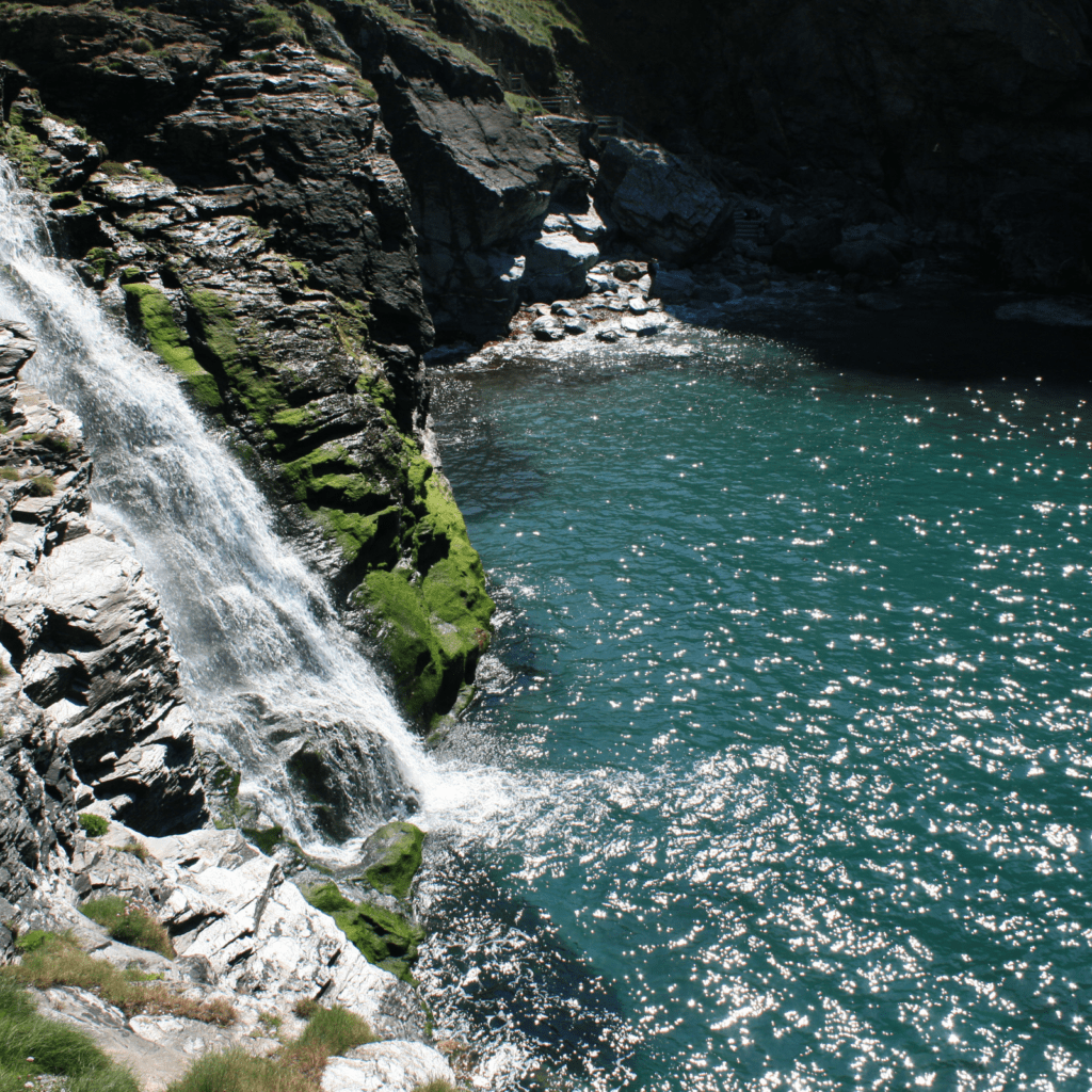 tintagel cornwall hidden waterfall with green grass on the cliff edges